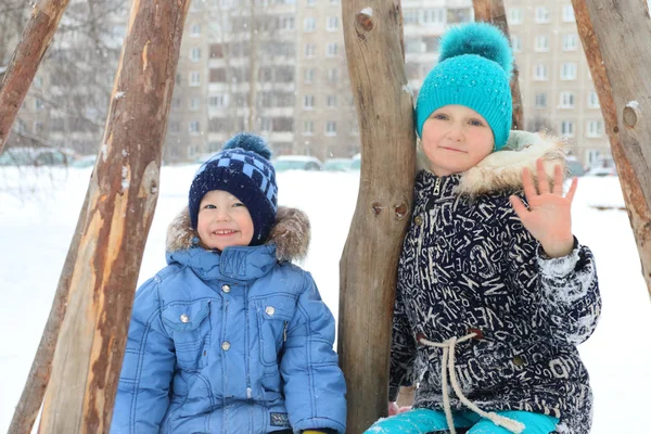 Glad tjej med lillebror smile under snöfall på vintern — Stockfoto
