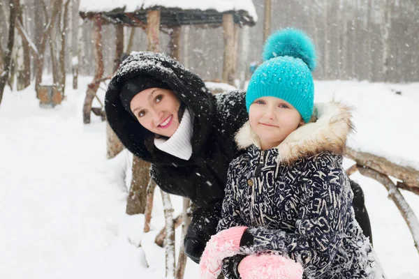 Счастливая мать с дочерью позируют в парке во время снегопада — стоковое фото