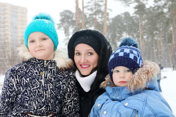 Lycklig familj (mor, dotter, son) pose under snöfall — Stockfoto