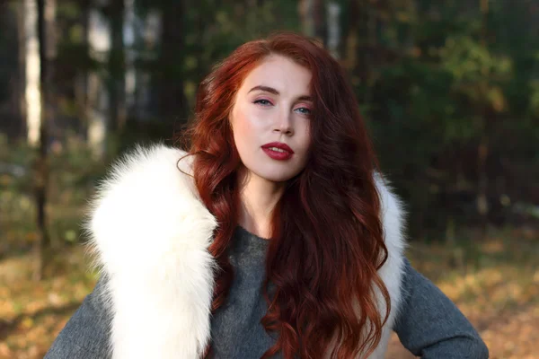 Pretty girl with make up and white fur stands in forest at sunny — Stock Photo, Image