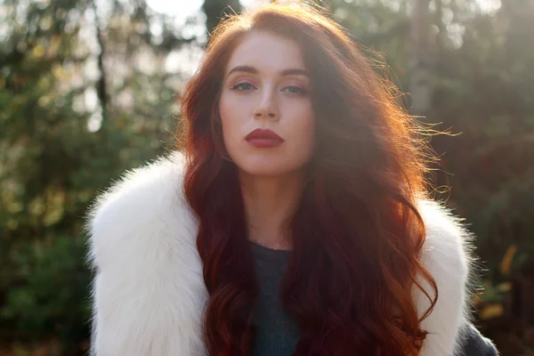 백색 모피 및 빨간 머리 예쁜 여 자가 숲에서 포즈 — 스톡 사진