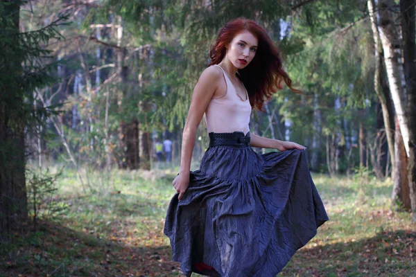 Jonge leuke vrouw in rok poses op wind in zonnige herfst bos — Stockfoto