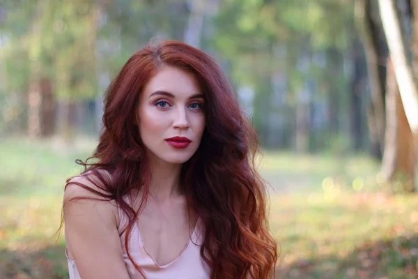 Сексуальная женщина в майке и с рыжими волосами позирует в осеннем лесу — стоковое фото