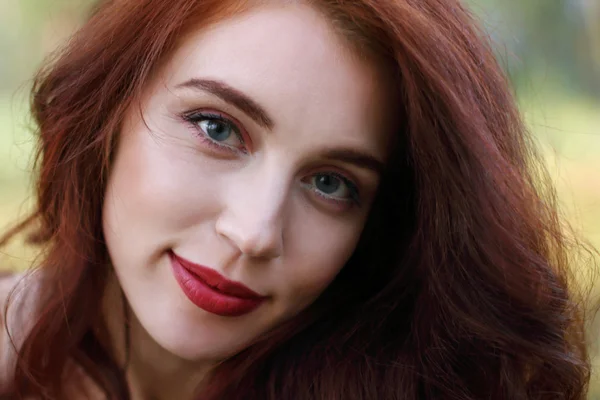 Mujer con el pelo rojo sonríe en el bosque, dof poco profundo, de cerca —  Fotos de Stock