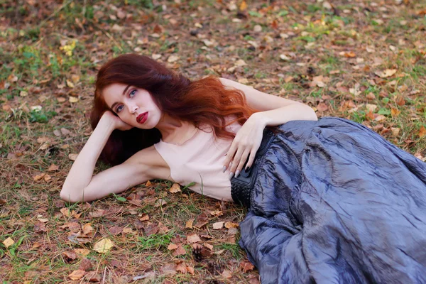 ベルト付けスカートで美しい少女が秋の乾燥した葉にあります。 — ストック写真