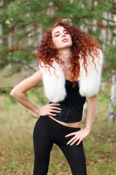 Frau im Korsett mit weißem Fell und lockigem Haar posiert im Wald — Stockfoto