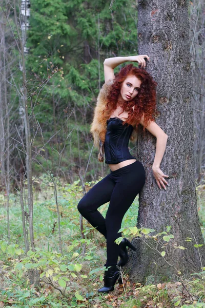 Beautiful girl in black brace poses near big tree in autumn — Stock Photo, Image