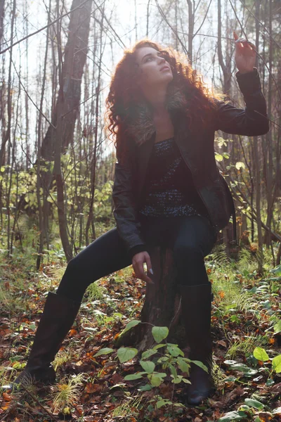 Beautiful girl in boots and jacket sits on tump — Stock Photo, Image