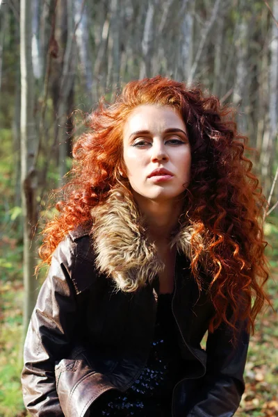 Beautiful woman in leather jacket poses in sunny autumn forest — Stock Photo, Image