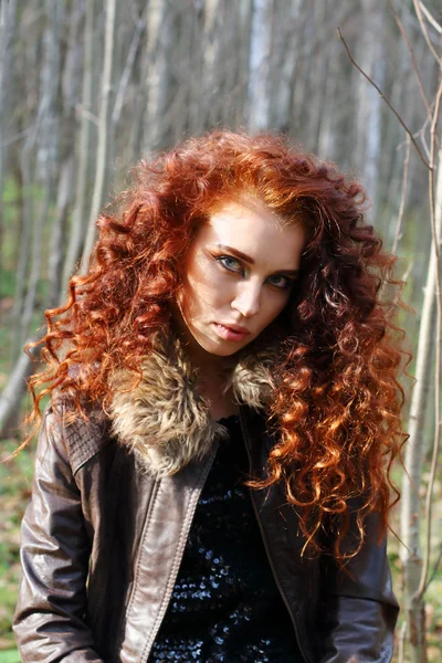 Beautiful woman with red hair in leather jacket poses — Stock Photo, Image