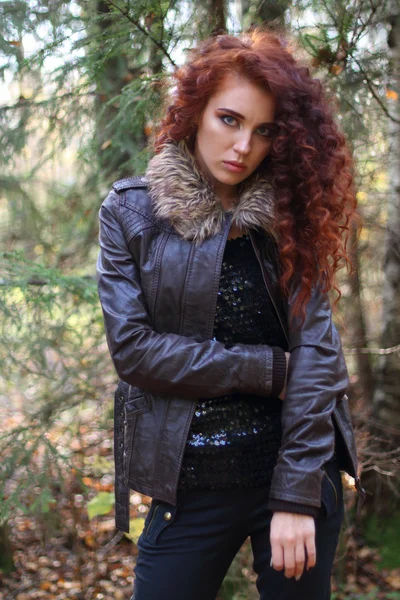 Girl with curly hair in leather jacket stands in sunny autumn — Stock Photo, Image