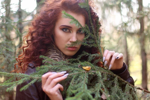 Beautiful woman looks through fir branch in forest, shallow dof — Stock Photo, Image