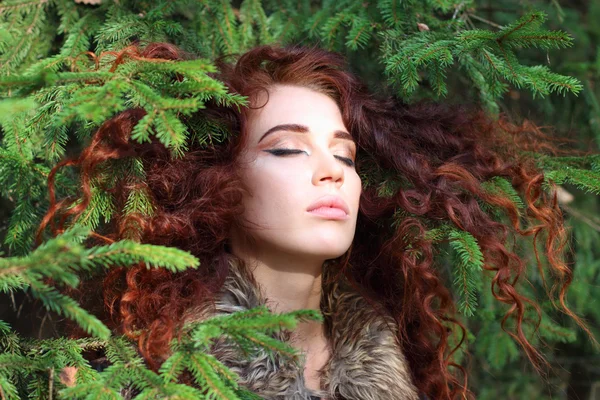 Young pretty woman with closed eyes among fir branches in forest — Stock Photo, Image