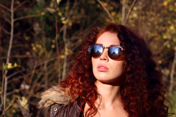 Hübsche junge Frau mit Sonnenbrille an einem sonnigen Tag im Herbstwald — Stockfoto