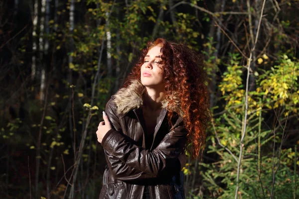Kapalı gözlerle ceketli genç güzel kadın güneş altında basks — Stok fotoğraf