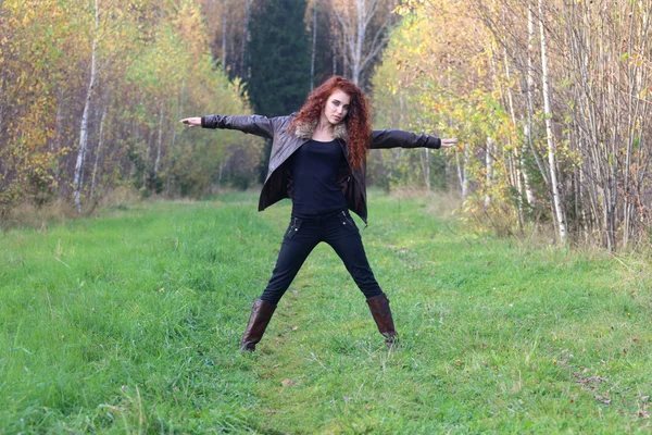 Pretty young woman in leather jacket poses on grass — Stock Photo, Image