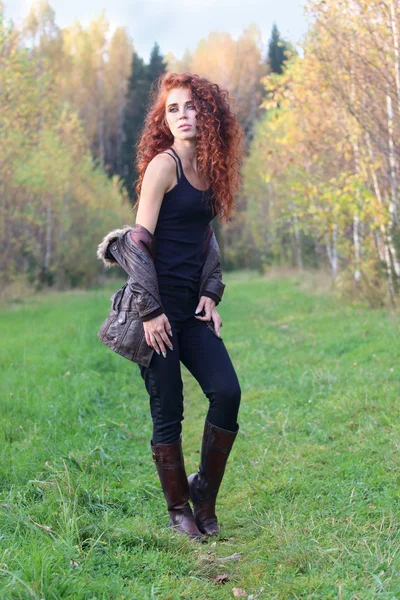 Beautiful woman in leather boots stands on grass — Stock Photo, Image