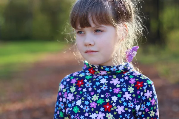 Sad little girl looks away in sunny green park, shallow dof, clo — Stock Photo, Image