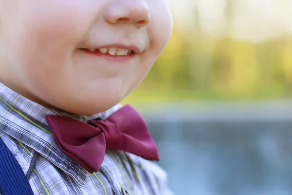 Подбородок и улыбающийся рот маленького симпатичного мальчика на галстуке под открытым небом — стоковое фото