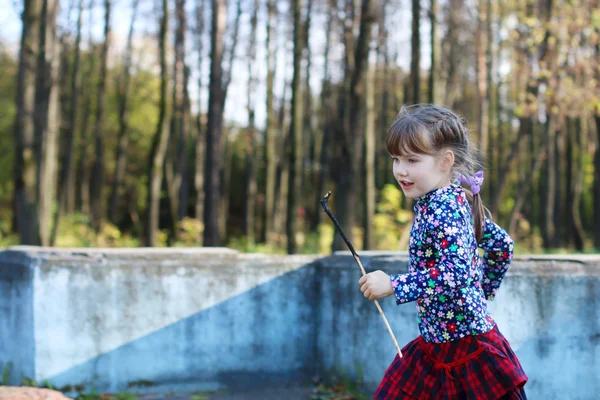 Nettes kleines Mädchen im roten Rock läuft im sonnigen grünen Park mit alten — Stockfoto