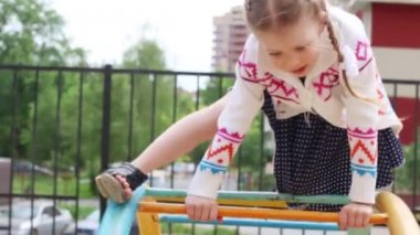 Elbiseli Llittle kız çocuk oyun alanı üzerinde yaz gününde tırmanıyor.