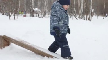 Mutlu küçük çocuk kış park kar yağışı sırasında oturum açmaya çalışır