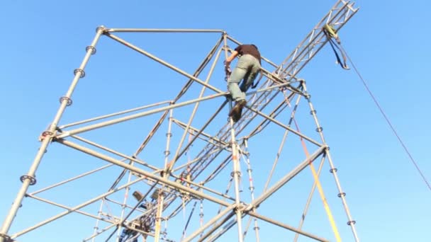 Niet-geïdentificeerde werknemer assembleert frame van buiten podium op zonnige dag — Stockvideo