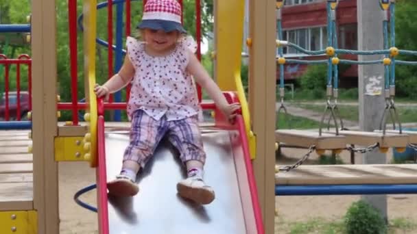 Feliz bonito menina desliza no playground brilhante no dia de verão — Vídeo de Stock