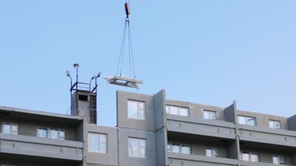 Part of grey apartment building of bearing-wall construction, hook of working crane with load — Stock Video