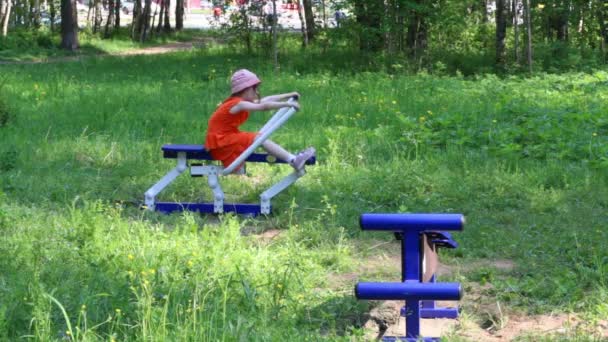 Kleines Mädchen macht Übungen auf Outdoor-Gymnastik im grünen Park — Stockvideo