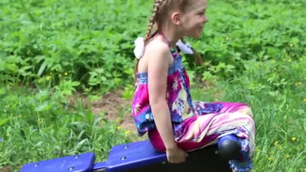 Liten flicka gör abs övningar på utomhus exerciser i grön park — Stockvideo