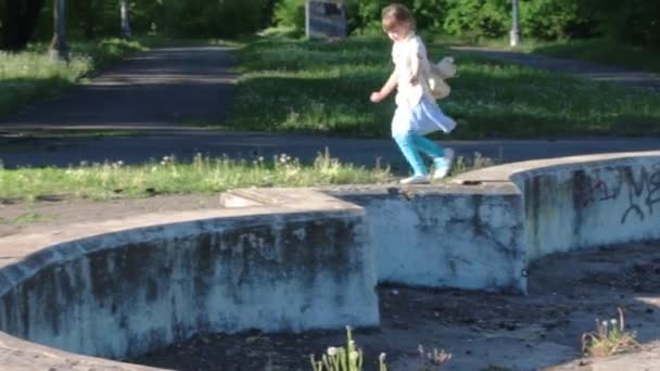 Pequena menina bonita corre na antiga fonte abandonada no parque de verão — Vídeo de Stock