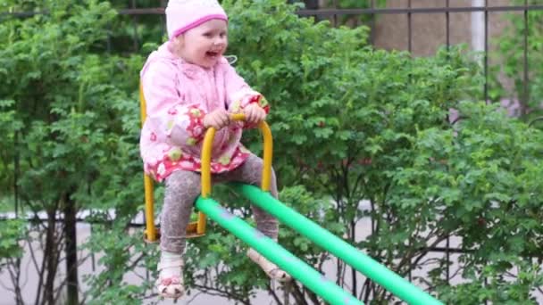 Krásná holčička jede na houpačku a směje se v letním dni — Stock video