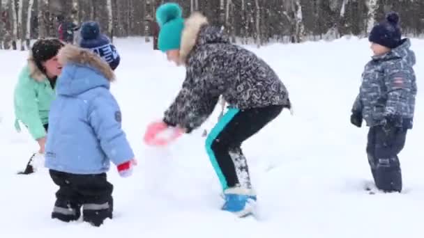 Žena a tři děti zvracet sníh během sněžení v parku
