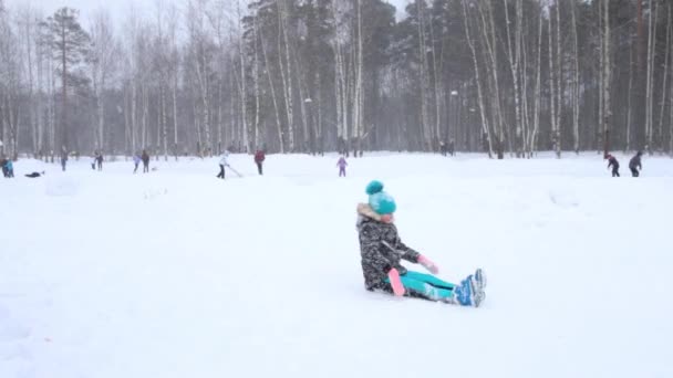 Flickan ramlar och gör första tumbling passera under snöfall på vintern — Stockvideo