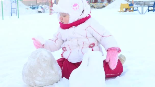 Menina feliz brinca com neve no playground no dia ensolarado de inverno — Vídeo de Stock