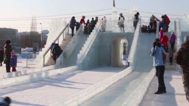 PERM, RUSSIA - FEB 14, 2016: Ice slide and people, Ice town in Perm - traditional winter attraction — Stock Video