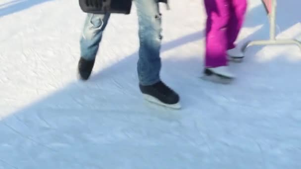 Ноги на коньках людей на катке в солнечный зимний день — стоковое видео