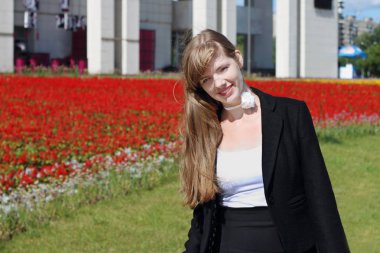 Siyah ceketli güzel kadın pozlar flowerbed içinde yakınındaki için güneşli