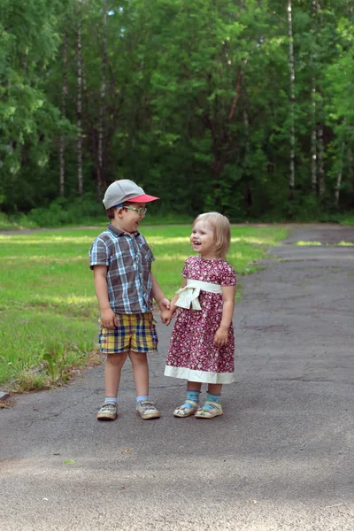Little pretty girl and boy laugh and hold hands in park at sunny — Stock Photo, Image