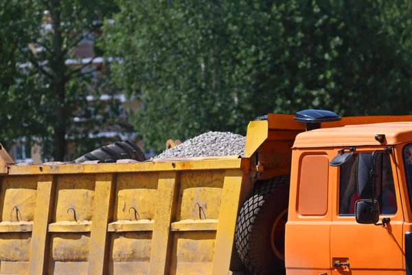 Parte de gran camión naranja con grava en el sitio de construcción en suma Imágenes de stock libres de derechos