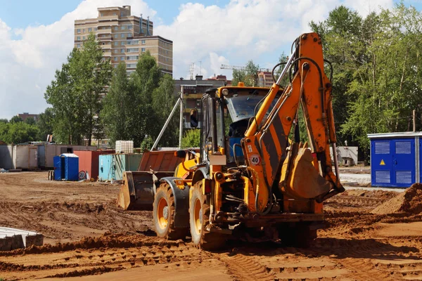 Tractor trabaja en el sitio de construcción con mucha arena en verano soleado Fotos de stock