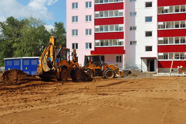 Два трактори працюють на піску на будівельному майданчику в літній сонячній д Стокова Картинка
