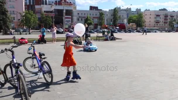 (slow motion) Happy girl (with model release) roller skates with balloon on central square — Stock Video