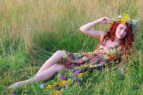 Hermosa mujer en corona con el pelo rojo se encuentra en el campo en verano —  Fotos de Stock