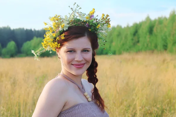 Pretty young woman in wreath poses among dry grass at summer day — Stock Photo, Image