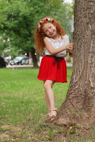 Pouco bonito menina posa perto de grande árvore no parque de verão, rasa dof — Fotografia de Stock