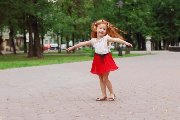 Little smiling girl with red hair dances in green summer park, s — Stock Photo, Image