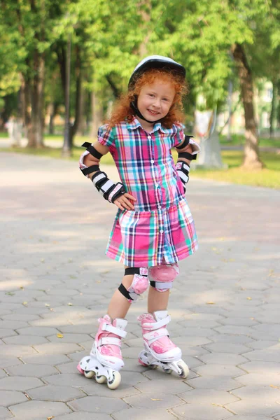 Happy little girl in helmet roller skates in summer park, shallo — Stock Photo, Image
