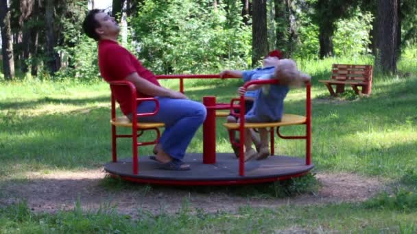 Father with two children ride on carousel in summer green park, slow motion — Stock Video